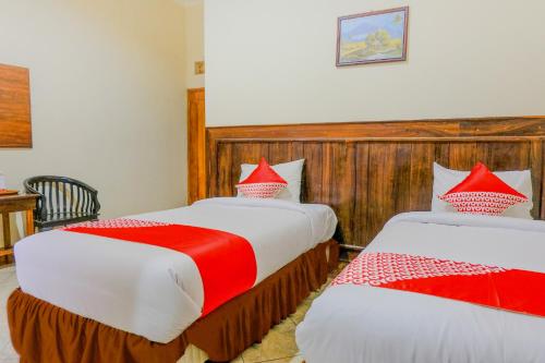 a bedroom with two beds with red and white pillows at Hotel O otel Graha Prima in Tamperan