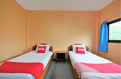 two beds in a room with two red pillows at OYO 588 Rose In Mansion in Trang
