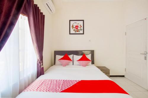 a bedroom with a red and white bed with a window at Hotel O D'soetta in Malang