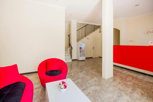 a living room with red chairs and a white table at Hotel O D'soetta in Malang