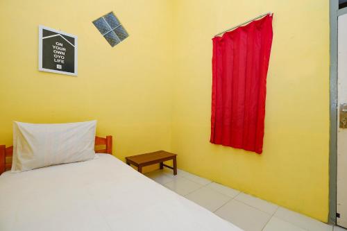 a bedroom with a bed and a red curtain at OYO Life 2867 Kos Kuning in Solo
