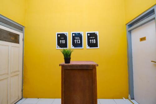 a yellow room with a table with clocks on the wall at OYO Life 2867 Kos Kuning in Solo