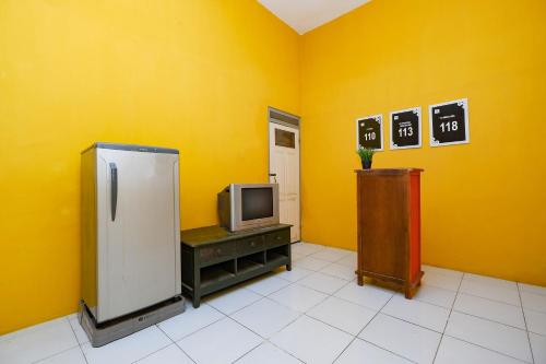 a yellow room with a refrigerator and a tv at OYO Life 2867 Kos Kuning in Solo