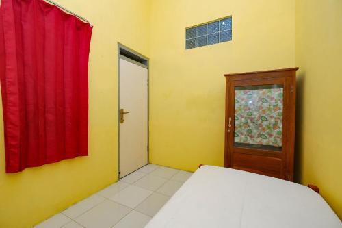 a bedroom with a bed and a red curtain and a door at OYO Life 2867 Kos Kuning in Solo