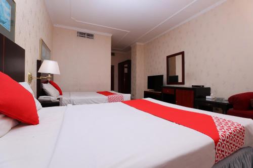 a hotel room with two beds with red and white sheets at OYO 112 Semiramis Hotel in Manama
