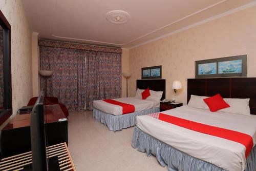 a hotel room with two beds and a television at OYO 112 Semiramis Hotel in Manama