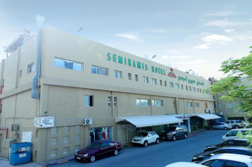a large building with cars parked in a parking lot at OYO 112 Semiramis Hotel in Manama