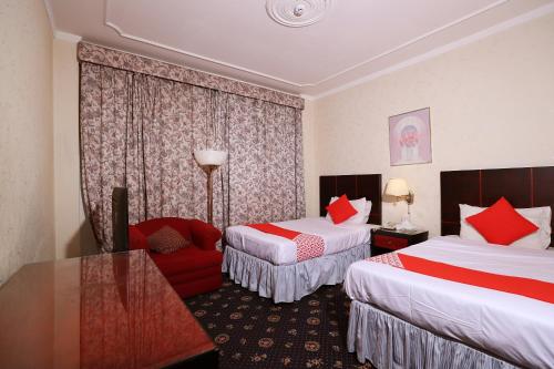 a hotel room with two beds and a red chair at OYO 112 Semiramis Hotel in Manama