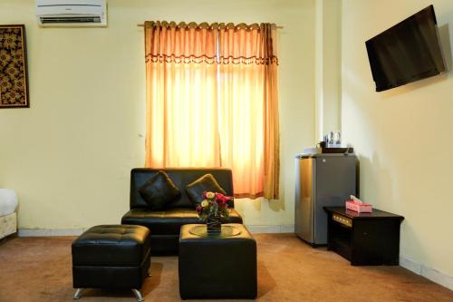 a living room with a black couch and a television at Collection O R.Sukamto Near Palembang Trade Center Mall in Palembang