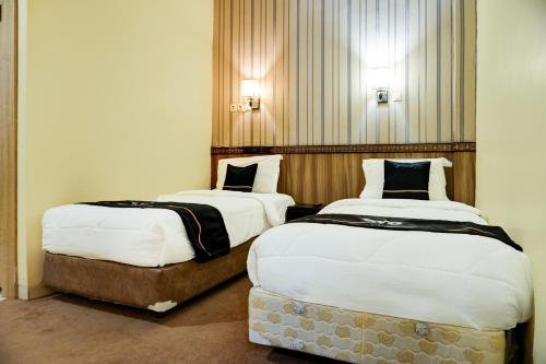 two beds in a hotel room with two at Collection O R.Sukamto Near Palembang Trade Center Mall in Palembang