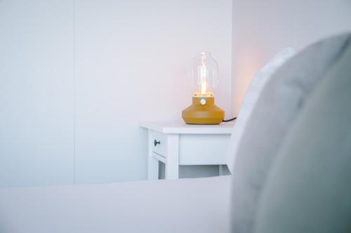 a lamp on a white table with a candle on it at Milli Vina Guesthouse in Borgarnes
