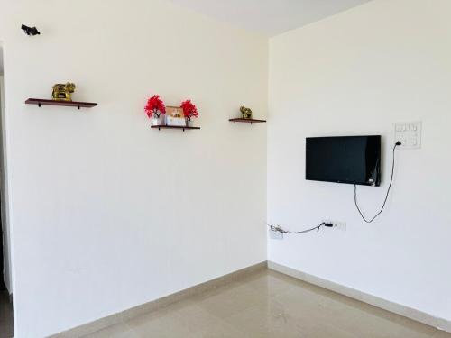 a room with a white wall with two shelves and a tv at Home Sweet Home in Thane