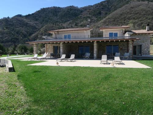 a house with chairs and a patio with mountains in the background at OASI DA VINCI in Tignale