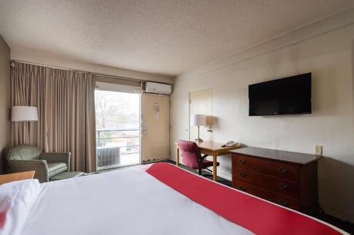 サムターにあるOYO Hotel Sumter SC Downtownのベッドと机とテレビがあるホテルの部屋