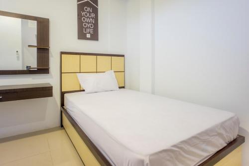 a white bed in a room with a mirror at OYO Life 2354 Rose House in Medan