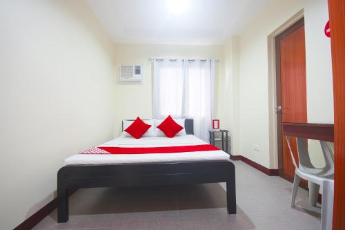 a bedroom with a bed with red pillows at OYO 567 Blue Horizon Hostel in Dumaguete