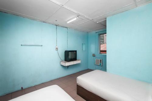 a blue room with two beds and a tv at Hotel O Gold Star Hotel in Sibu