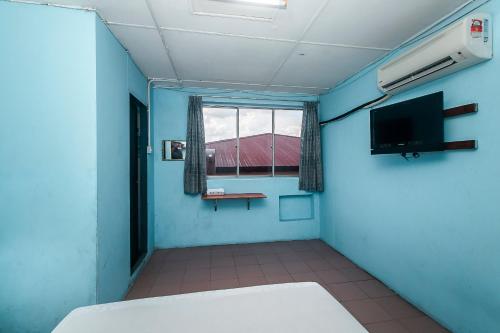 a room with blue walls and a window and a television at Hotel O Gold Star Hotel in Sibu