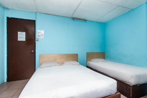 two beds in a room with blue walls at Hotel O Gold Star Hotel in Sibu