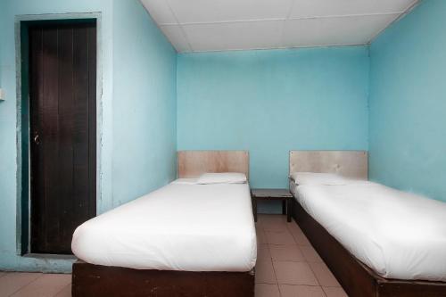 two beds in a room with blue walls at Hotel O Gold Star Hotel in Sibu