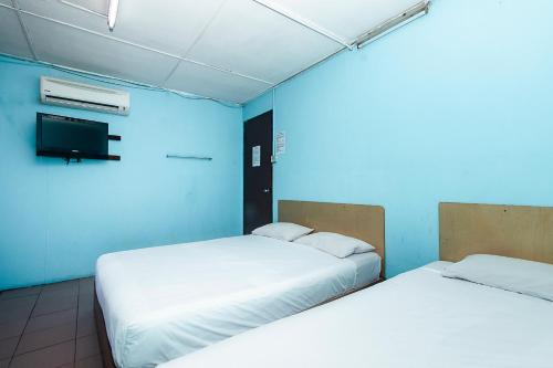 two beds in a room with a blue wall at Hotel O Gold Star Hotel in Sibu