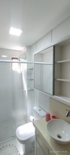 a white bathroom with a toilet and a sink at Apartamento coração meia praia in Itapema