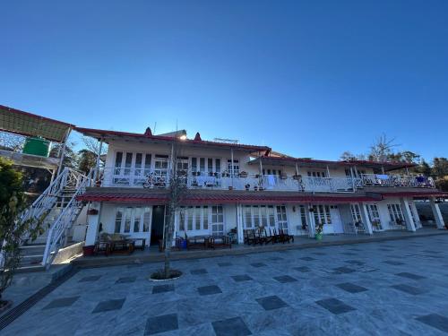 a large building with tables and chairs in a courtyard at The Whitegrove Retreat in Mukteswar