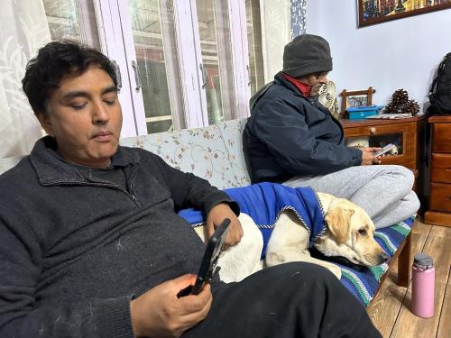 a man sitting on a couch with a dog at The Whitegrove Retreat in Mukteswar