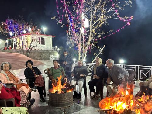 a group of people sitting around a fire at The Whitegrove Retreat in Mukteswar