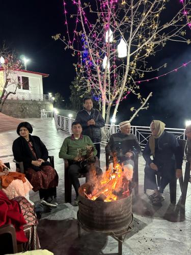 a group of people sitting around a fire at The Whitegrove Retreat in Mukteswar