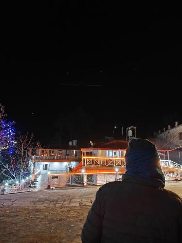 a person sitting in front of a building at night at The Whitegrove Retreat in Mukteswar