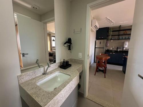 a bathroom with a sink and a kitchen with a table at Apartamento Sunset Residence 1208 in Dourados