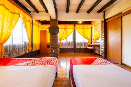 two beds in a room with yellow curtains at Capital O 2640 Cottage GS Rumah Kayu Syariah in Batureo 1