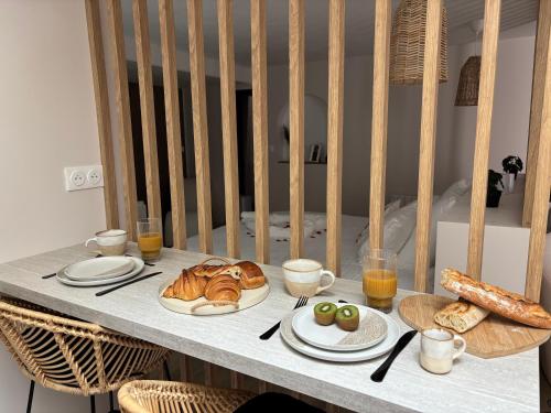 a table with plates of food and bread and glasses of orange juice at Suite Banjar-Luxe,Balnéo & Sauna in Saint-Aubin-dʼAubigné