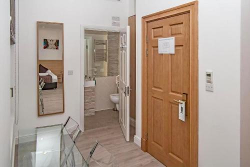a hallway with a wooden door and a bathroom at NOX Kensington in London