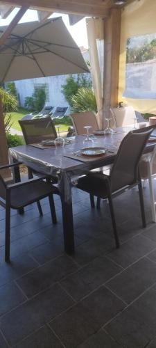 - une table avec des verres à vin et des chaises sous un parasol dans l'établissement Charmante maison 6/7 personnes., à Olonne-sur-Mer