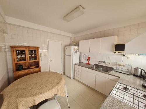 Una cocina con una mesa y un refrigerador blanco. en Departamento en Playa Varese, en Mar del Plata