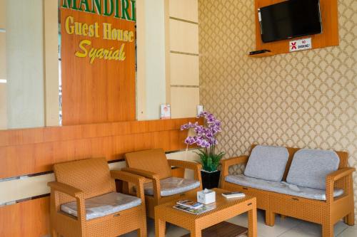 a waiting room with chairs and a table and a tv at Hotel O Mandiri Guest House Syariah in Bukittinggi