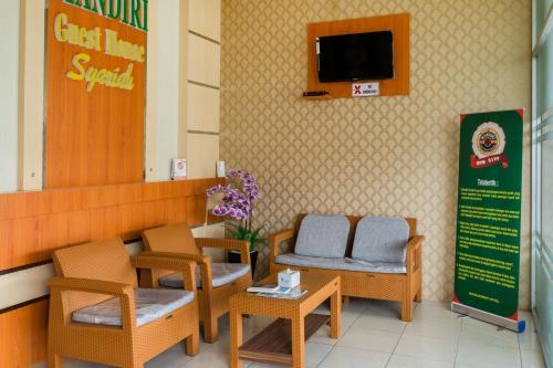 a waiting room with chairs and a tv on the wall at Hotel O Mandiri Guest House Syariah in Bukittinggi