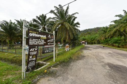 a sign on the side of a road with palm trees at Hotel O Otternest @ Gunung Pulai 2 in Pontian Besar