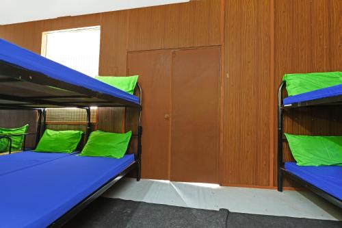 two bunk beds in a room with green pillows at Hotel O Otternest @ Gunung Pulai 2 in Pontian Besar