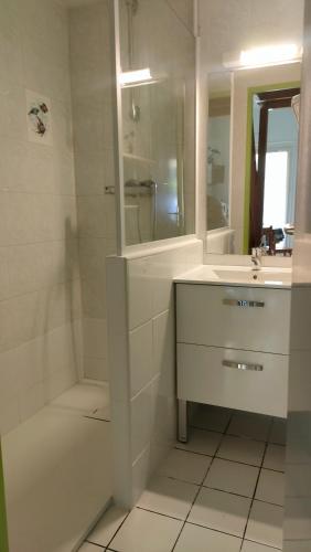 La salle de bains blanche est pourvue d'une baignoire, d'un lavabo et d'une douche. dans l'établissement Maison Bord de mer Vendres-Plage Valras-Plage, à Vendres