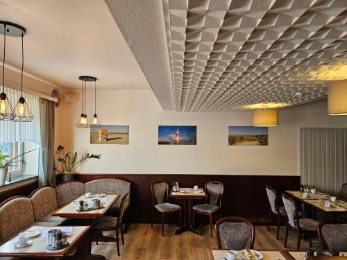 a restaurant with tables and chairs and a coffered ceiling at Hotel Pension Loose in Borkum