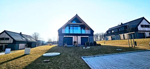 a large house with a gambrel roof on a field at Apartmán Nad Údolím Šumava in Prachatice