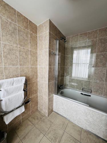 a bathroom with a tub and a shower with towels at The Rutland Hotel in Douglas