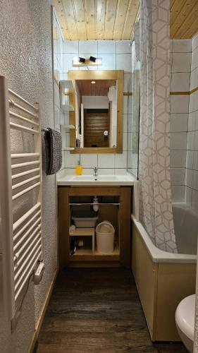 une salle de bain avec un lavabo, une baignoire et un miroir dans l'établissement Belle Plagne 2050m Chaleureux studio 4 personnes, à La Plagne Tarentaise
