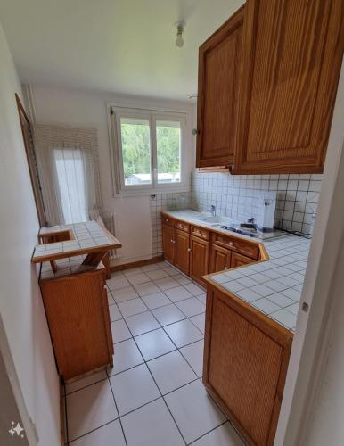 Il comprend une cuisine avec des placards en bois et du carrelage blanc. dans l'établissement Saint-Jean-de-Braye Combleux Une simple petite maison, à Saint-Jean-de-Braye