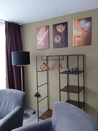 a living room with a chair and a lamp and paintings at B&B Uit de Kunst Anna Paulowna in Bingelrade