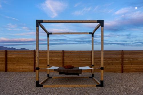 a metal bed with a canopy in front of a fence at Umbra Acres in Twentynine Palms