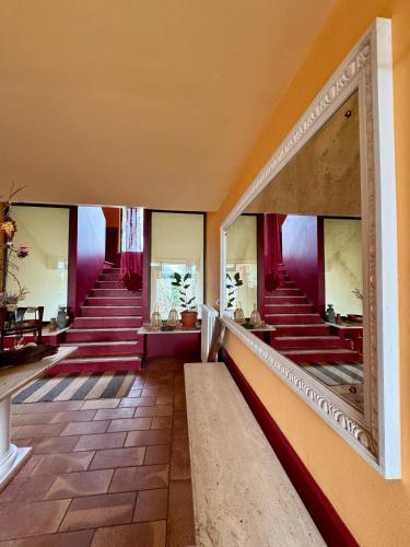 a hallway with red stairs and a mirror at B&BLe Tre Gemme in Montechiarugolo